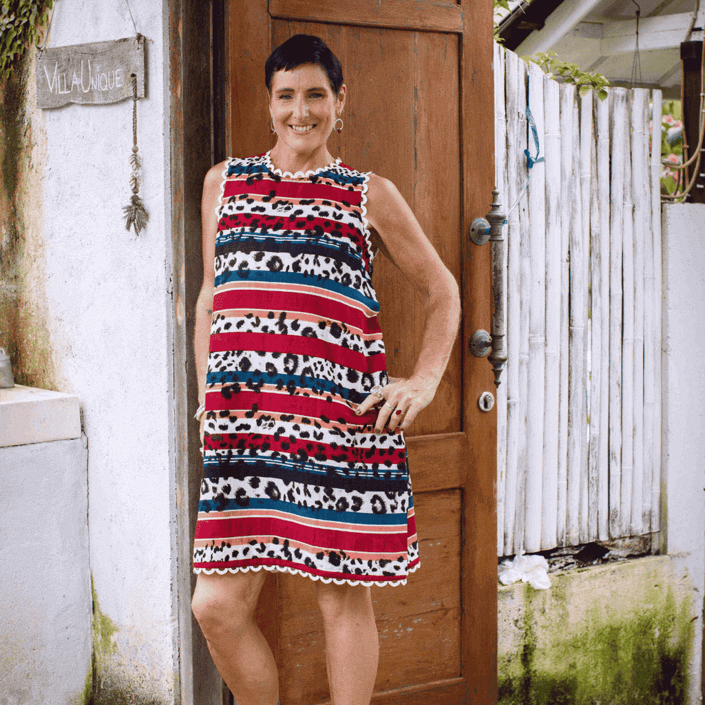 Woman wearing a red, white, and blue patterned dress standing in front of a wooden door.