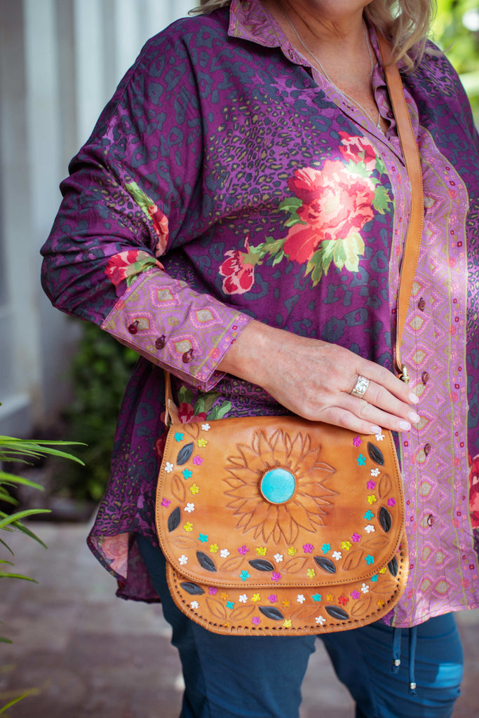 Taleeta - Purple Hibiscus Jungle Blouse - Blue Cotton Pants & Leather Bag - Facing Front Left - Midway Closeup Shot